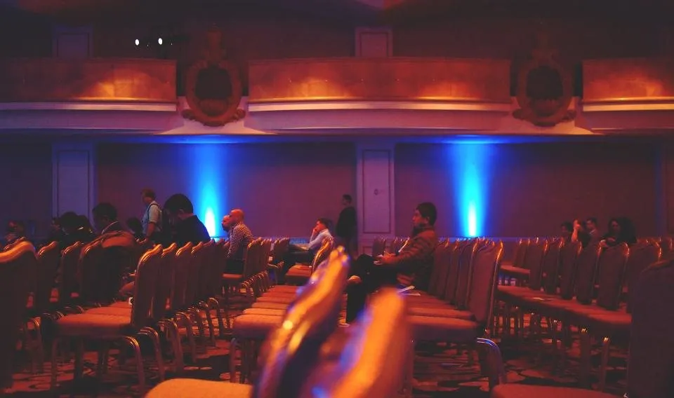 Salón corporativo con iluminación escénica y público sentado